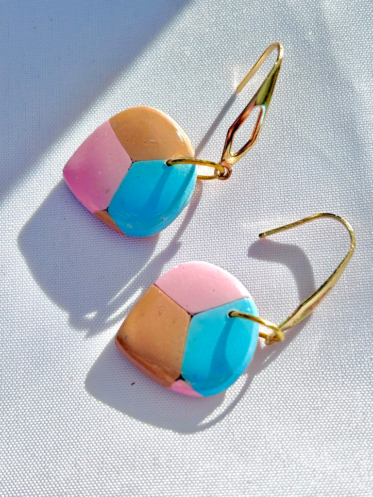 pastel geometric polymer clay earrings with blue, pink, and beige segments, hanging on gold-tone dangle hooks