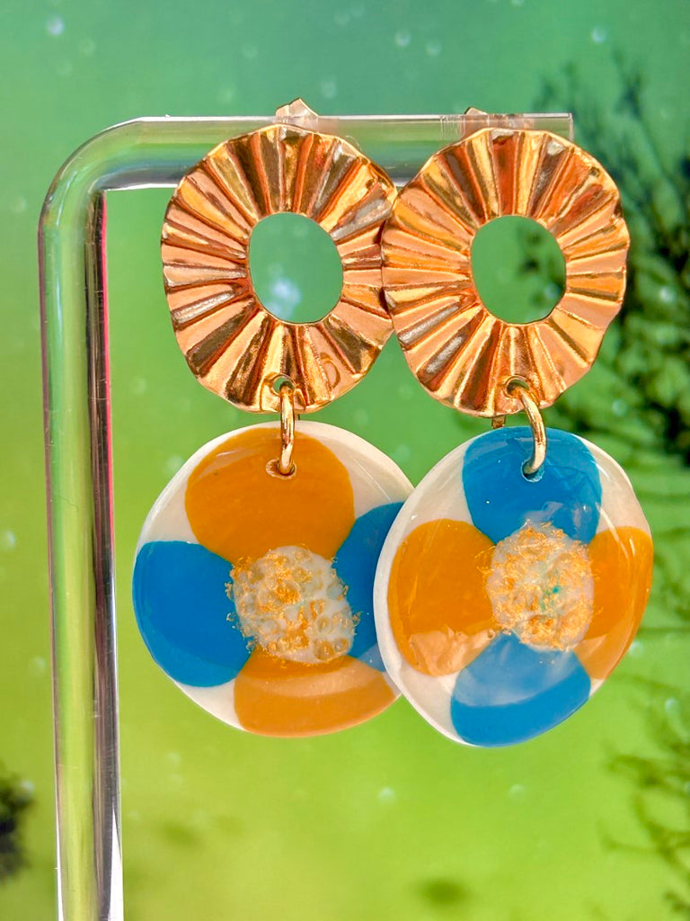 polymer clay floral earrings with large golden sunburst studs, featuring blue and orange petals.