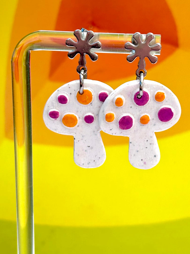 white mushroom-shaped polymer clay earrings with purple and orange dots on floral studs