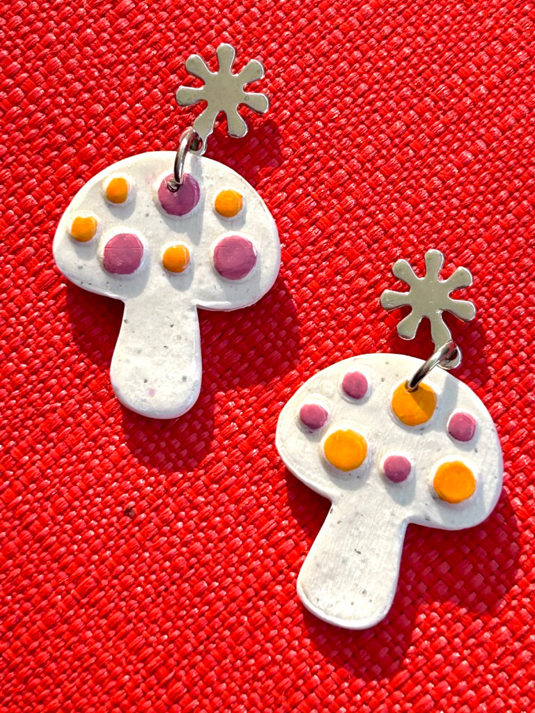 white mushroom-shaped polymer clay earrings with purple and orange dots on floral studs