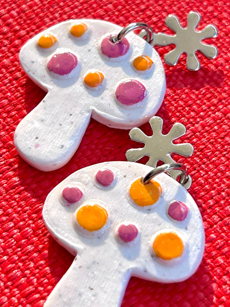 white mushroom-shaped polymer clay earrings with purple and orange dots on floral studs