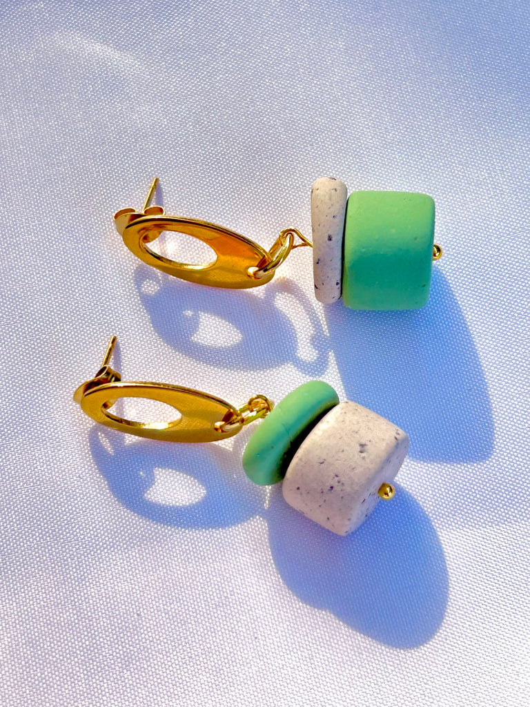 Asymmetrically stacked sage and coffee-speckled polymer clay earrings with golden oval studs