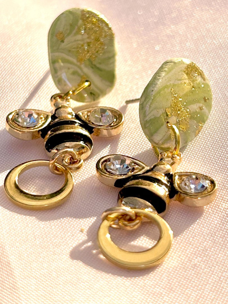 polymer clay earrings with green studs, bee charms, and gold hoop details